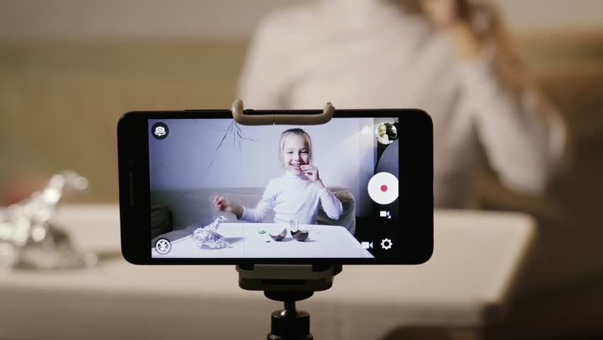 A static frame of a lovely baby girl in a white jacket unpacking an egg with a surprise. Young blogger writes a video for publication and likes in home Studio | Shutterstock HD Video #1024290545