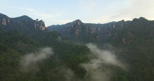 Aerial video above tropical forest in a sunny day with clouds. Amazing mountain aerial view. Flying through the spectacular rock mountain landscape.