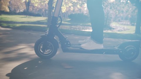 Slow Motion of Modern Man Using Electric Scooter in Sunny Park 4