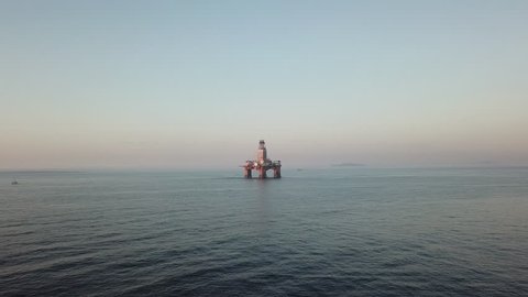 Drone approaches big oil platform anchored in Cape Town at sunset