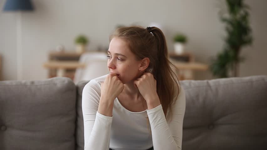 Stressed upset teen girl worried about problem sitting alone at home, sad nervous young woman feeling anxious troubled with unwanted pregnancy, frustrated after mistake, afraid to make wrong decision | Shutterstock HD Video #1024307150