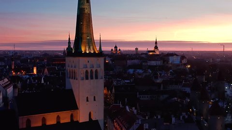 Aerial shot entering medieval Tallinn old town after colorful sunset. Shot passing St Olaf's church opening onto Toompea hill