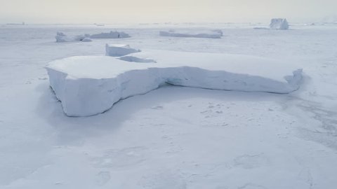 Tabular Iceberg Stuck In Frozen Ocean Aerial View. Snow Covered Antarctica Lagoon Nature Seascape at Peninsula Shore. Winter Peaceful Cold Iceland Sea Floe Top Drone Shot Footage 4K (UHD)