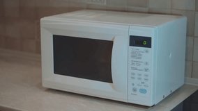Heated food in the microwave. Female hand puts pies in the microwave in the lunch box. Cooking in the microwave. 4k video.