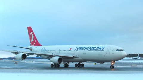 oslo airport norway - ca january 2019: huge airplane turkish airlines a340 taxiing turning panning right side view winter scenery small folow me car behind