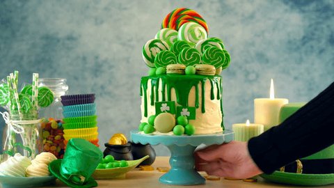 St Patrick's Day theme lollipop candyland drip cake on colorful party table setting.