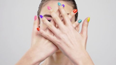Beautiful woman with bright vivid makeup. Sexy adult girl with colorful nails on the hands.  Pink make-up of eyes. Closeup caucasian face of a  fashion model. Slow motion footage. Trendy and style.