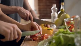 Close up shot of man hands slicing carrot and female hands cutting tomato on wooden cutting board for salad on the table with healthy food in the kitchen. Side view. - Powered by Shutterstock - Get 15% off with code: PIKWIZARD15