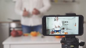 Man on the kitchen with fruits filming video. Vlogging concept.