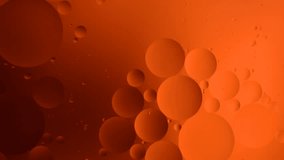 orange gradient oily drops circling in water with colorful background, close-up 