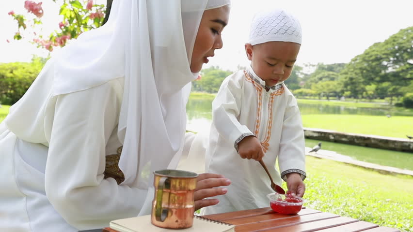 Muslim family kids and mother relaxing and picnic at park.
