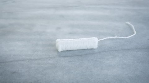 Woman knocking a tampon out of frame with a menstrual cup in slow motion. Represents choosing a zero waste, eco-friendly option over a disposable one.