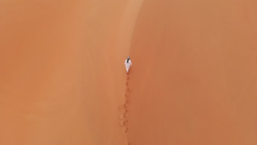 Emirati man walking in massive sand dunes of Rub Al Khali desert