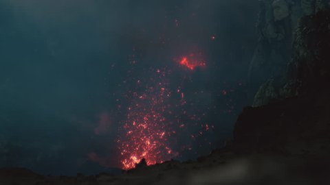 SUPER SLOW MOTION CLOSE UP: Cinematic shot of pieces of molten magma flying high up in the air out of an active volcanic crater in Sicily. Dangerous hot lava is blasted into the air during an eruption