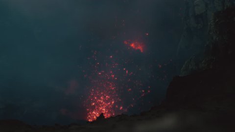 SUPER SLOW MOTION, CLOSE UP, DOF: Dangerous hot magma is bursting in air during a violent volcano eruption in Sicily. Bright orange lava is scattered around the rugged rocky crater of Mount Yasur.