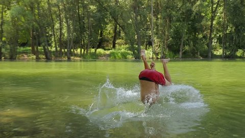 Guy jumping from rope swing hitting the water face first
