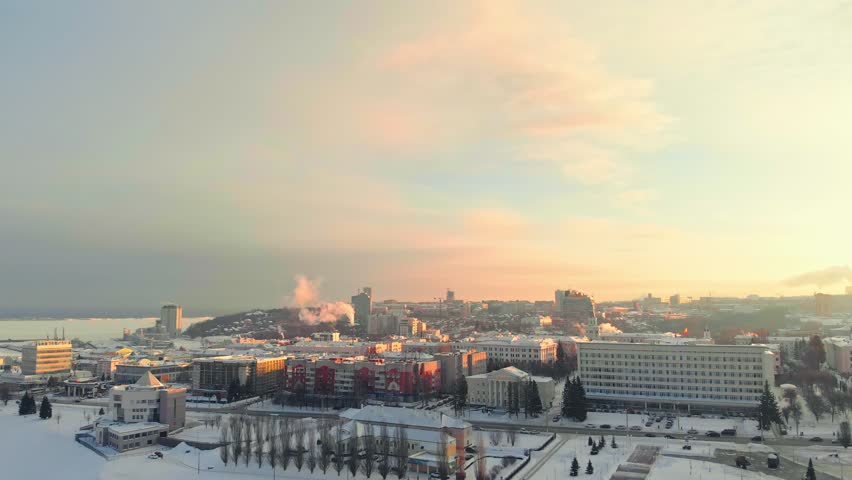 Aerial view of modern residential buildings next to the frozen river in the city. Aerial shooting, cityscape at sunset, sunrise
