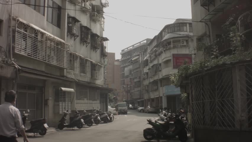 Asian slum ghetto neighborhood with wire frame metal bars on the one apartment building and scooter bike pedestrian walking in Taiwan