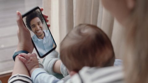mother and baby having video chat with father using smartphone waving at infant enjoying communicating with family on mobile phone connection