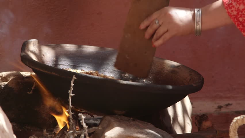 Old Moroccan Woman Preparing Dinner by Fire with Hands and Piece of Wood