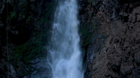 manzanilla de la paz, Jalisco / Mexico - 11 18 2018: Tilt up of a waterfall and some men doing a rappel in it one inside the water another in the dry part in maraton cañonero 2018