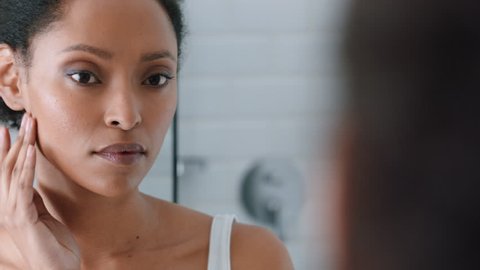 portrait beautiful african american woman looking in mirror at perfect skin enjoying natural complexion winking confidently getting ready at home
