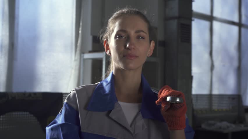 Portrait of a beautiful cute girl in a uniform standing with a spanner in the service station