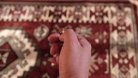 Close up view of a Muslim man hand counting prayer beads or tasbih on a prayer mat. Selective focus. Panning shot.