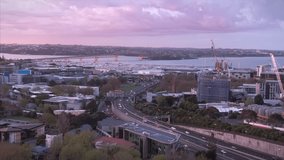 Aerial View Of Auckland City Skyline and traffic on the motorway at sunset, New Zealand
