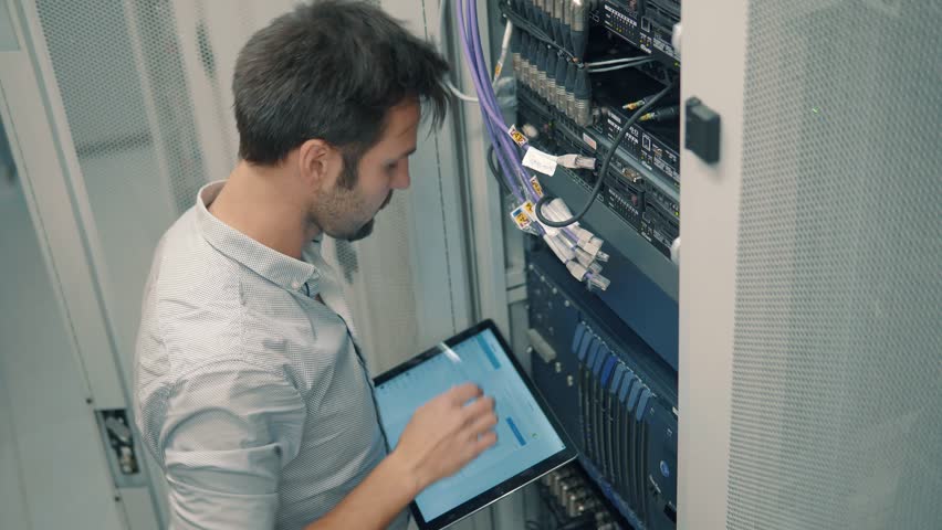 Male It Technician Engineer With Tablet Work In Server Room In Data Center. Male It Technician Engineer With Tablet Work In Server Room In Data Center.  Male IT Engineer Working In A Data Center With  Royalty-Free Stock Footage #1024448690
