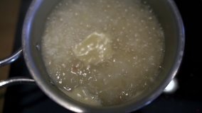 Closeup of pan with rice in boiling water (slow motion)