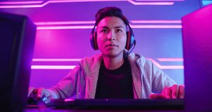 Young Asian Handsome Pro Gamer having live stream and playing in Online Video Game