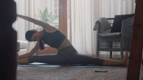 healthy asian woman exercising at home practicing stretching in living room enjoying morning fitness workout