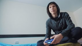young teen and joystick man hooded sweater absorbed In online video game. boy teenager in the hood playing video games on the console on the gamepad. . Controller console gamepad. Gaming man holding
