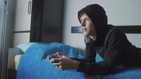young teen and joystick man cybersport hooded sweater absorbed In online video game. boy lifestyle teenager in the hood playing video games on the console on the gamepad. Controller console gamepad