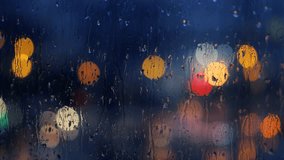 The Raindrops On Window stock video clip features close-up raindrops streaming down a window. You can see beautiful bokeh light effects in the background created from passing cars. Use this real foota