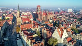 Gdansk, Poland. Old city with Gothic St. Mary church, city hall with clock tower, Dluga Street and old historic houses. Aerial approaching video in sunrise light