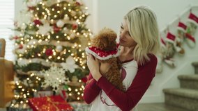 Portrait of smiling woman hugging dog and looking at camera on Christmas / Vineyard, Utah, United States