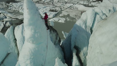 High angle scenic view of ice climber approaching peak of glacier using hooks / Palmer, Alaska, United States