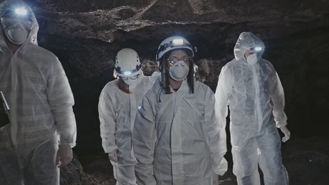 Group of scientists in bio-hazard suits in a cave