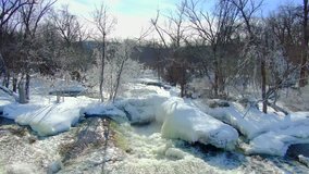 Winter wonderland, ice glazed trees glistening by steaming rapids, below dam.
