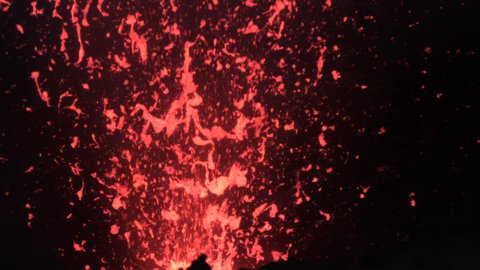 SLOW MOTION, CLOSE UP: Active volcanic crater emitting bright red pieces of lava during eruption. Stunning close up view of particles of glowing magma erupting from Mount Yasur. Powerful nature.