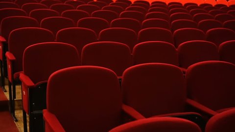 Rows of empty red velvet seats inside a theater or opera.