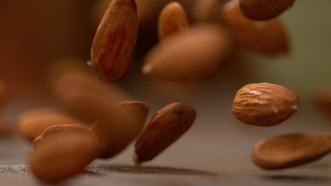SLOW MOTION, MACRO, DOF: Healthy almond kernels fall from the sky and bounce off the table. Homegrown organic almonds bouncing around the kitchen counter. Ripe unpeeled brown almonds falling down.