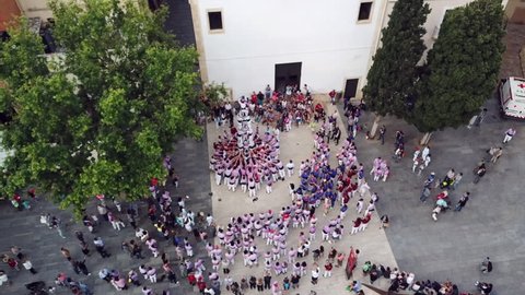 incredible upper view people in traditional dress train to make human castle on square among old houses in Tarragona