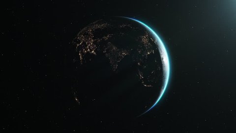 The Earth slowly rotating in space, backlit by the sun with the lights of the planet's cities visible on the surface. The sun drifts across frame as the world turns, revealing the continents at night.