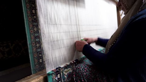 Traditional woman weaving Turkish carpet. Making Persian carpet by hand in classic style. Creating handmade patterned rug using proper technique.