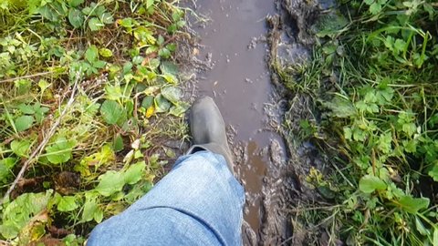 Slow motion walking with Wellington boots though mud and leaves