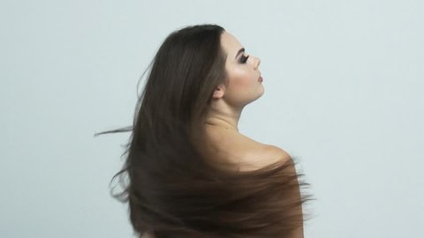 Woman moves long hair. Rear view. Girl shakes long straight hair. Female model is fluttering hair.   Slow motion footage. Rear view.