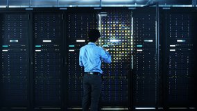 The Concept of Digitalization of Information: IT Specialist Standing In front of Server Racks with Laptop, He Activates Data Center with a Touch Gesture. Animated Visualization of Network Data - Powered by Shutterstock - Get 15% off with code: PIKWIZARD15